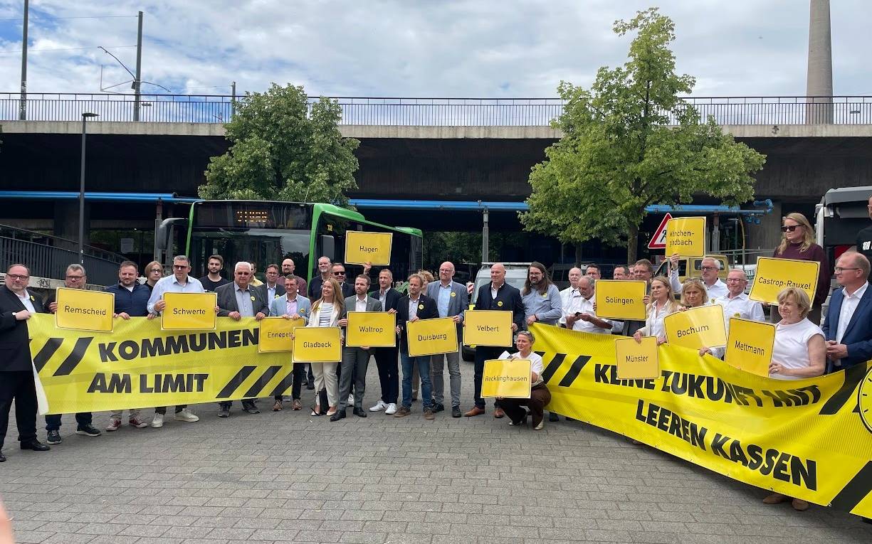 Bürgermeister und Kämmerer NRWs halten Plakate hoch
